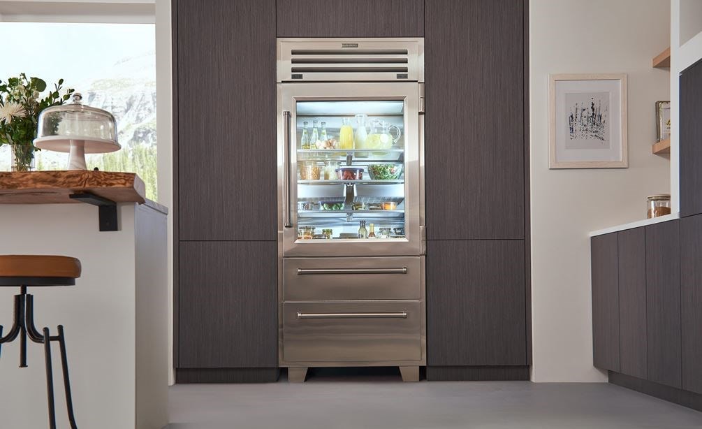 sub zero french door fridge with see through glass door full of food in a home kitchen with two bottom drawers for freezer and flex drawer 